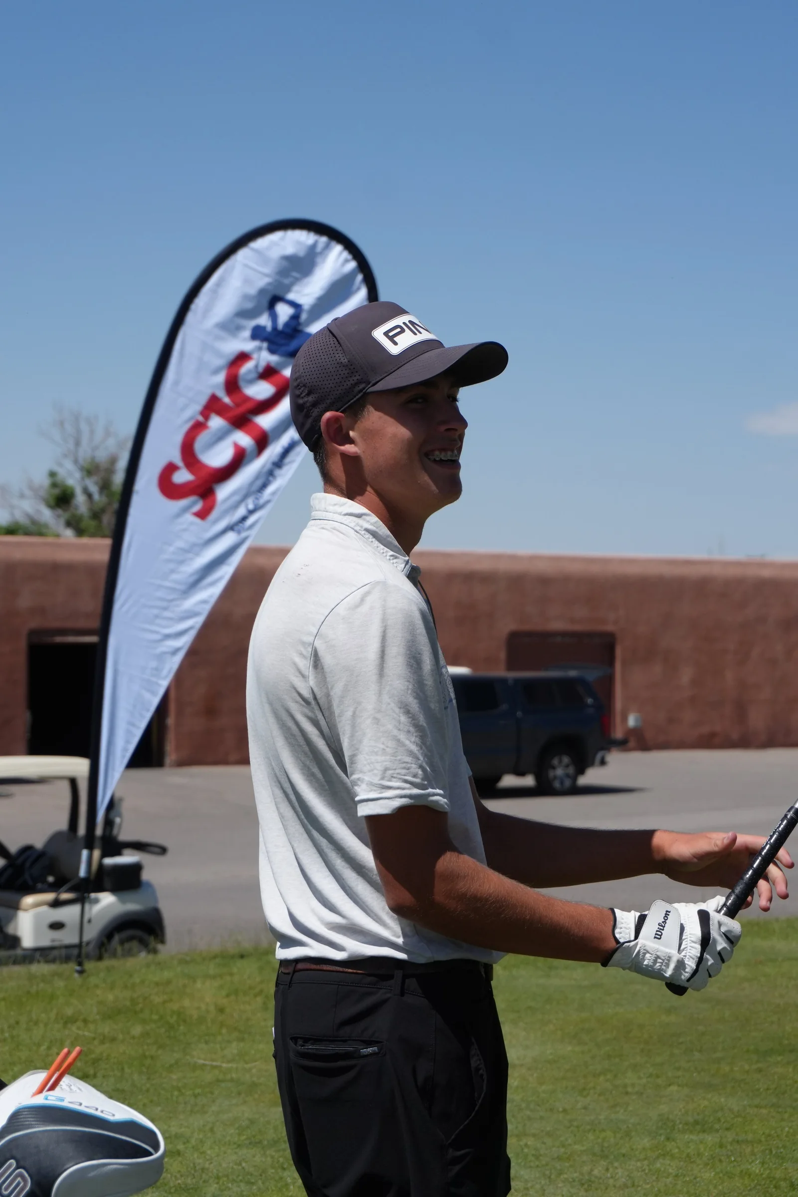 A junior golfer holds the flagstick on a green.