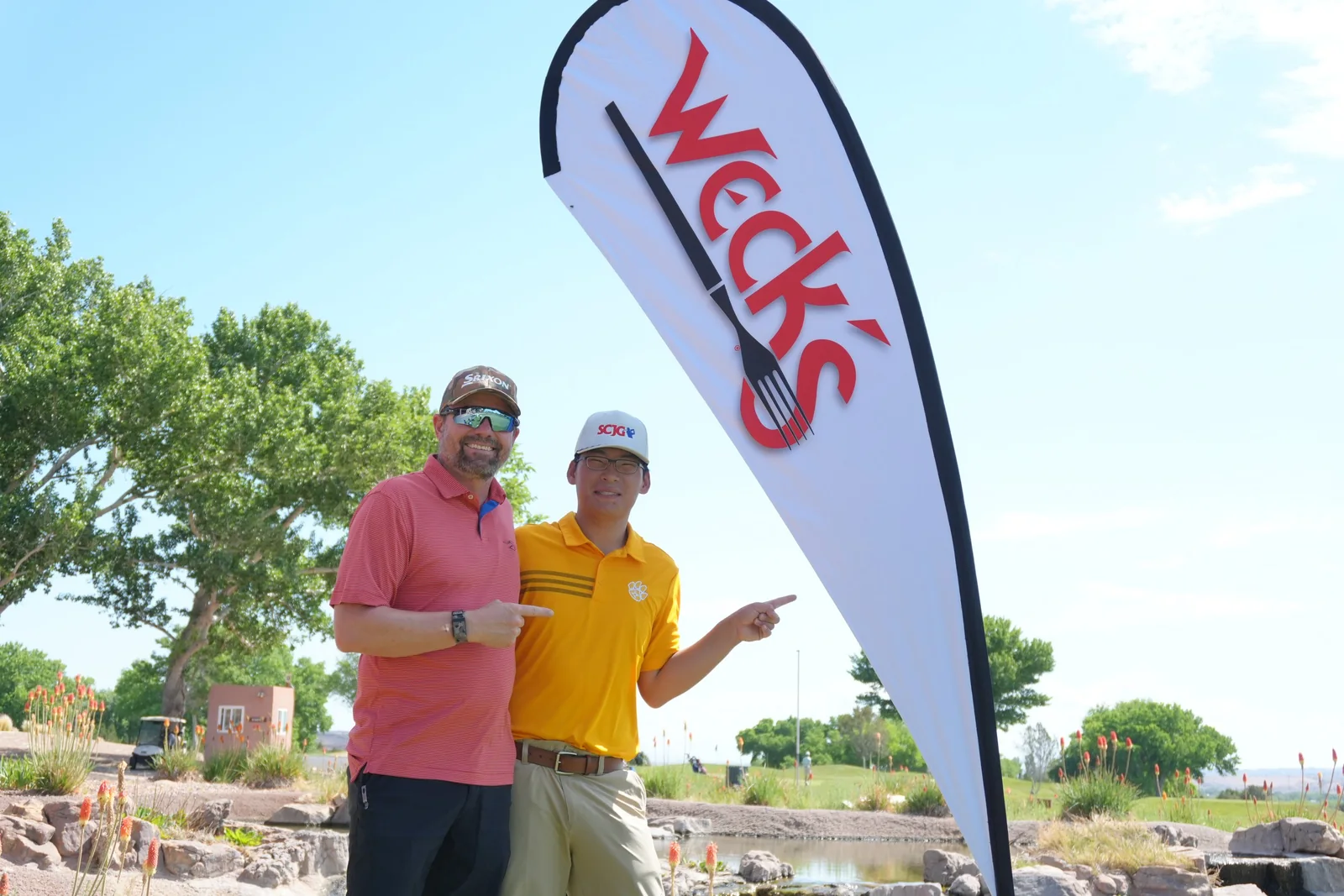 Two men stand beside a Weck’s sponsor flag.